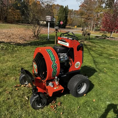 J&J Enterprises commercial leaf vacuum machine on a lawn during fall cleanup